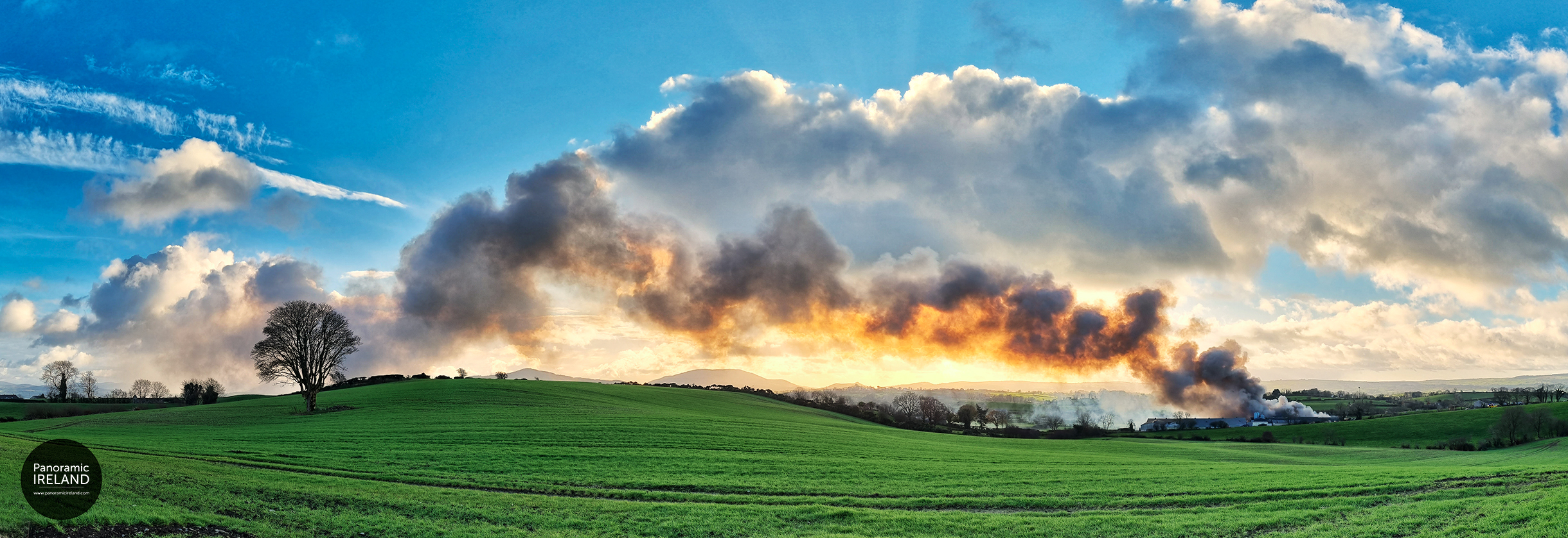 Landscape of Smoke and Fire A pig farm ablaze with thick, billowing smoke obscures the beauty of the Northern Ireland countryside